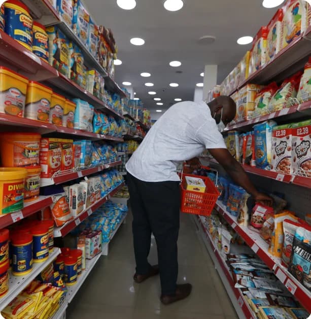 A shopper reaching for a product on a supermarket shelf